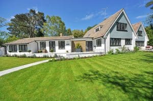 Well-maintained white house with a clean roof and siding, surrounded by a freshly mowed green lawn, showcasing strong curb appeal.